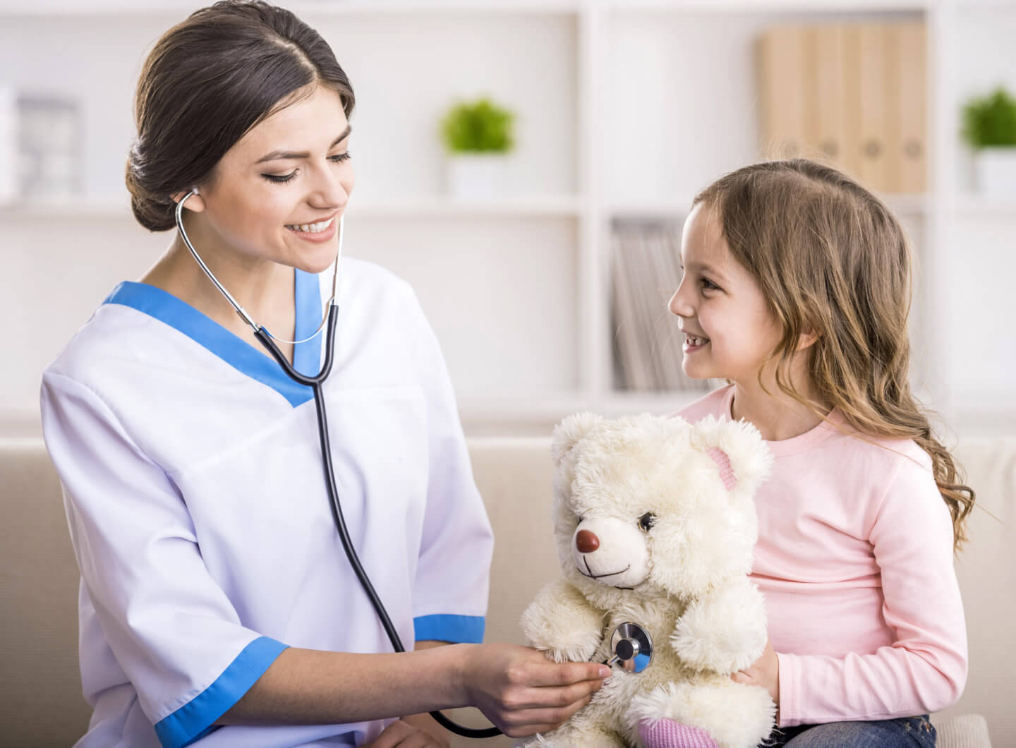 Home healthcare worker uses stethoscope on child's teddy bear.